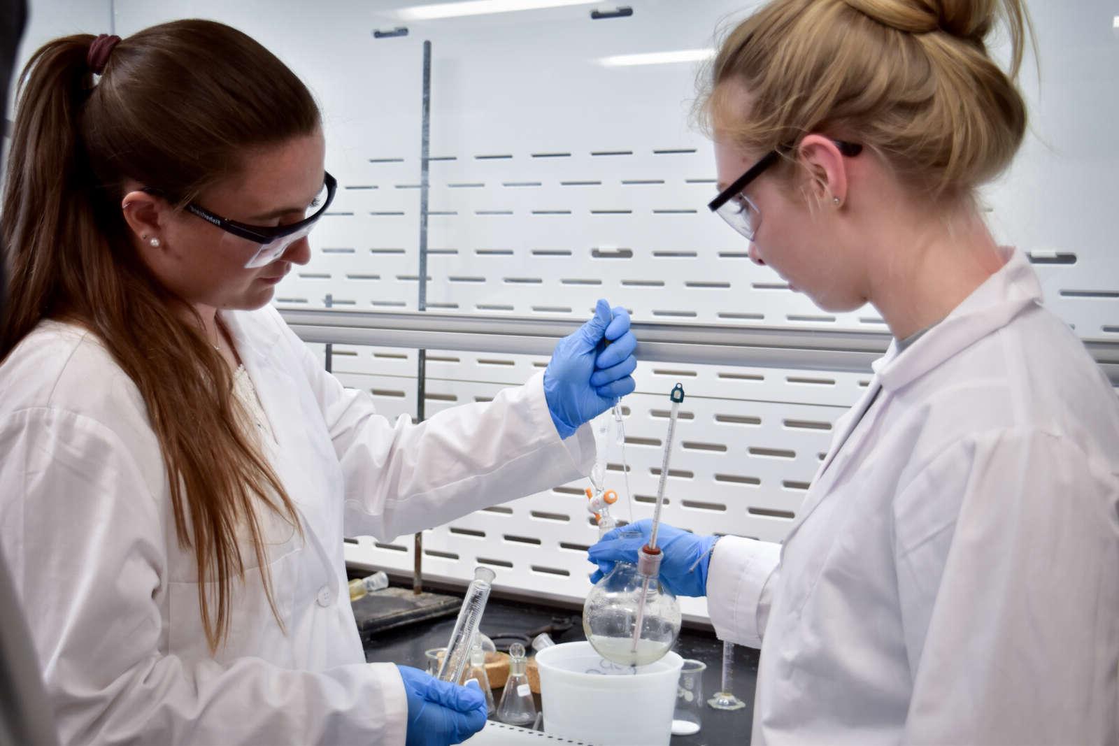 students working in a labcoats for a chemistry project